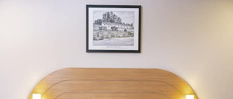 A hotel room with a large bed, two bedside tables, a framed picture on the wall, and a telephone on one of the tables.