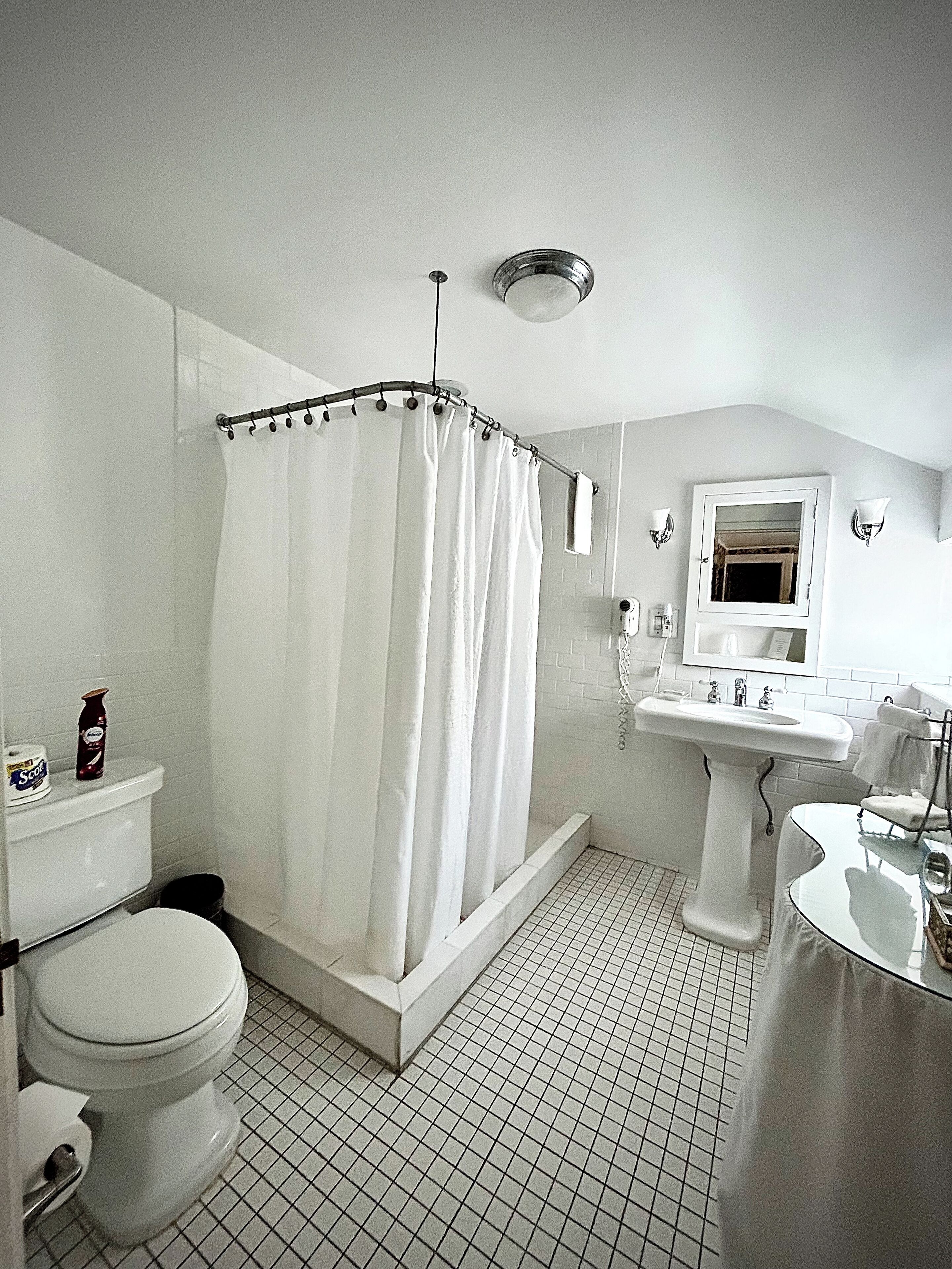 Un baño con ducha, inodoro, lavamanos y espejo.