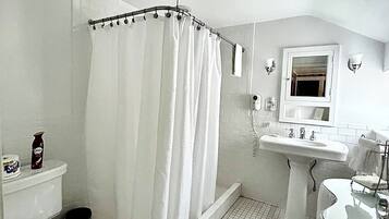 Un baño con ducha, inodoro, lavamanos y espejo.