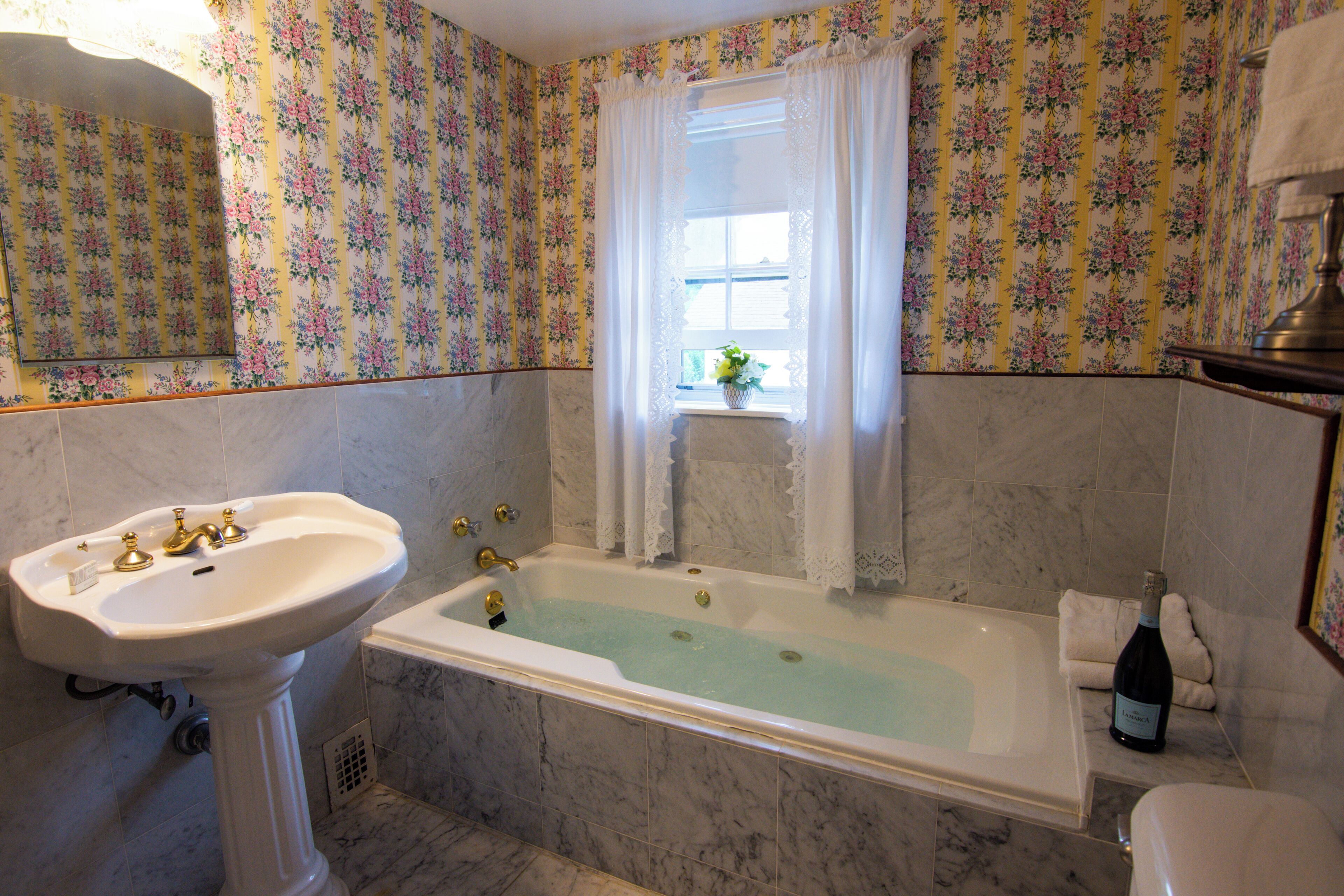 A bathroom with a sink, bathtub, and floral wallpaper.