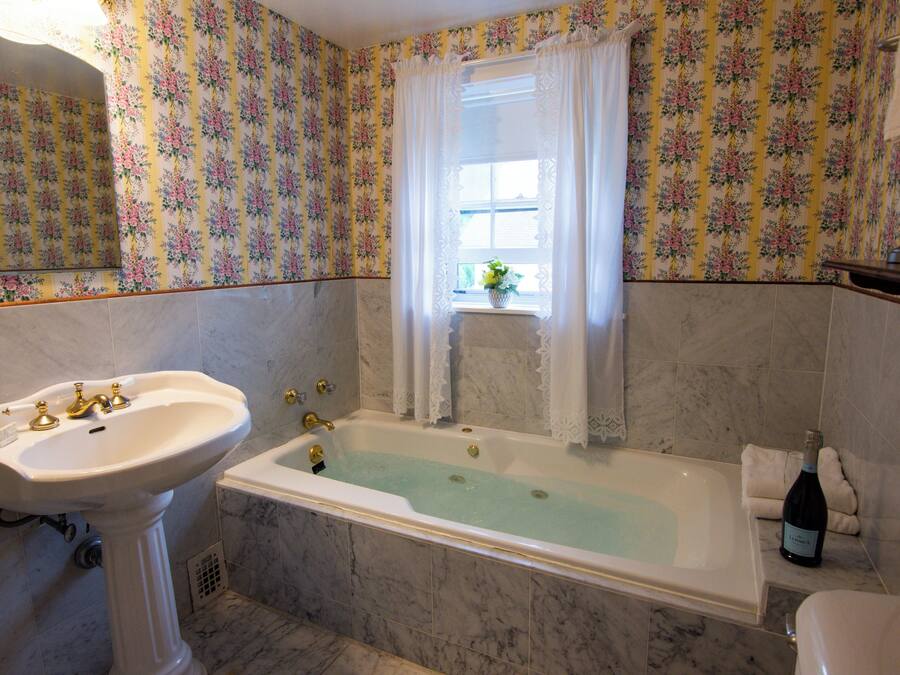 A bathroom with a sink, bathtub, and floral wallpaper.
