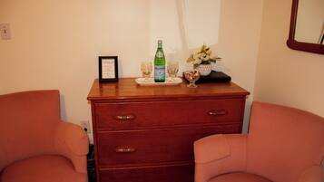 A wooden dresser with drawers, a framed certificate on top, and two glasses on a tray.