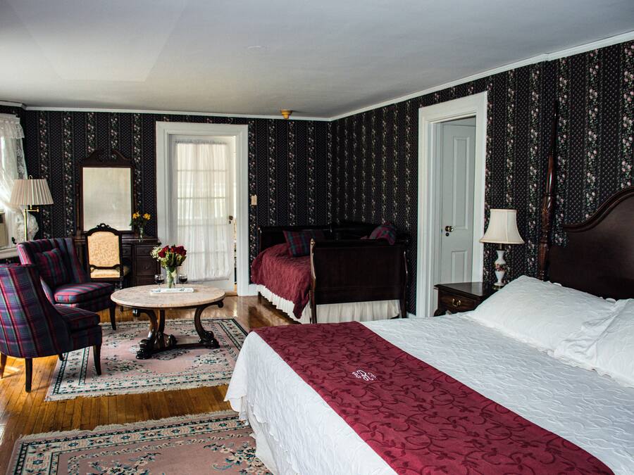 A hotel room with a bed, a chair, a table, and a mirror.
