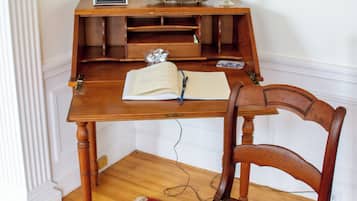 Una scrivania in legno con una lampada, un quadro incorniciato e una pianta in vaso.