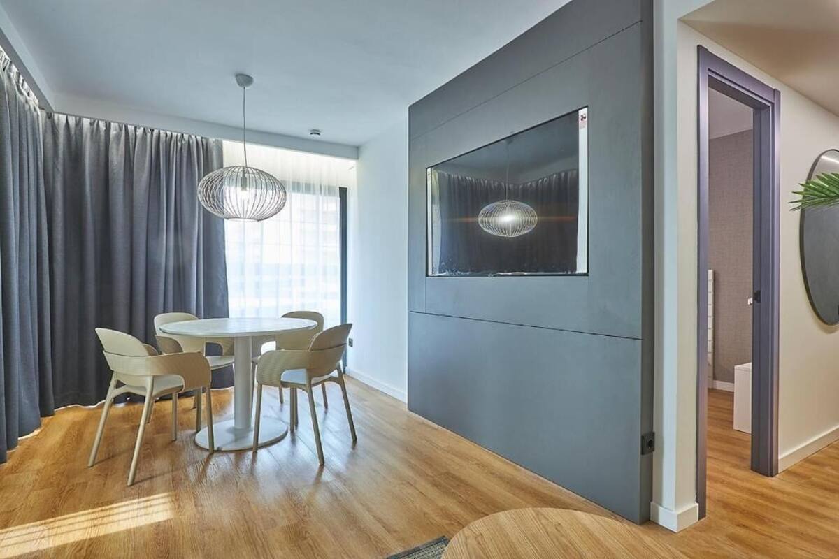 Un espace repas moderne avec une table ronde et des chaises, un luminaire suspendu et une grande œuvre d’art encadrée au mur.