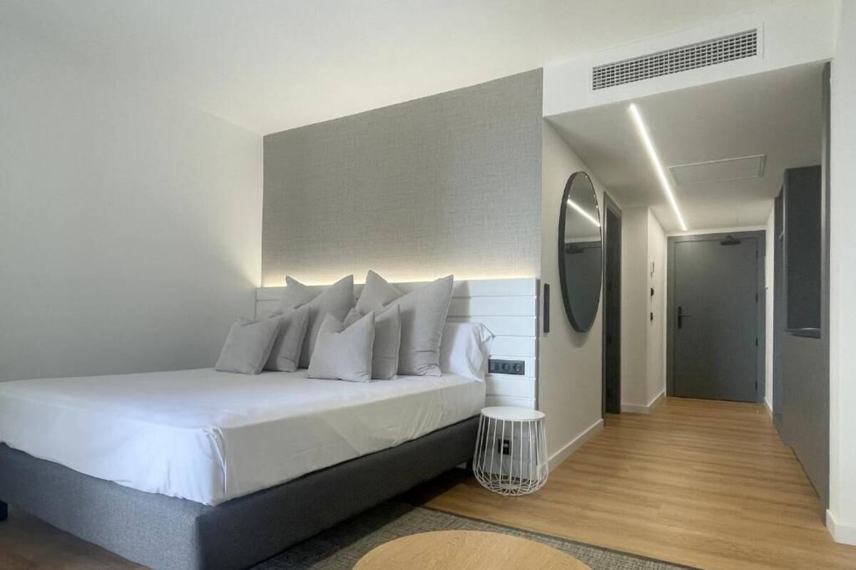 Une chambre à coucher moderne avec un grand lit, une table de chevet, un miroir et un dressing.