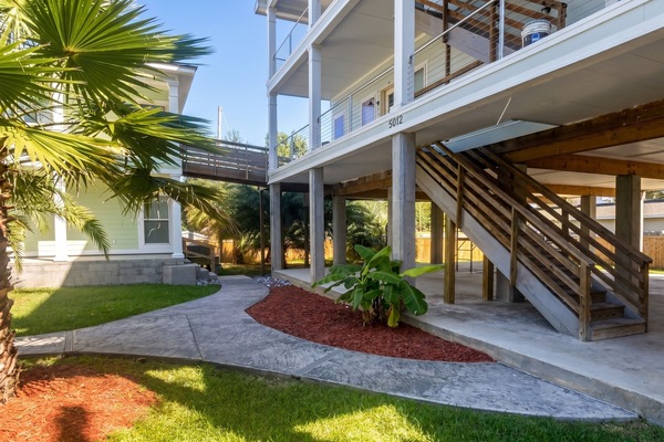 Elevated coastal home with tropical landscaping and inviting walkway