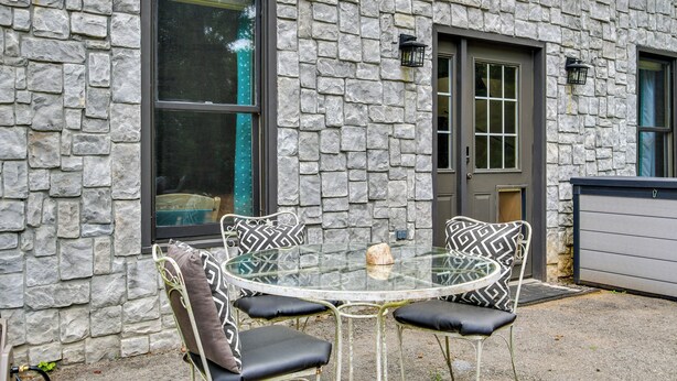 A stone building with a glass table and four chairs with patterned cushions.