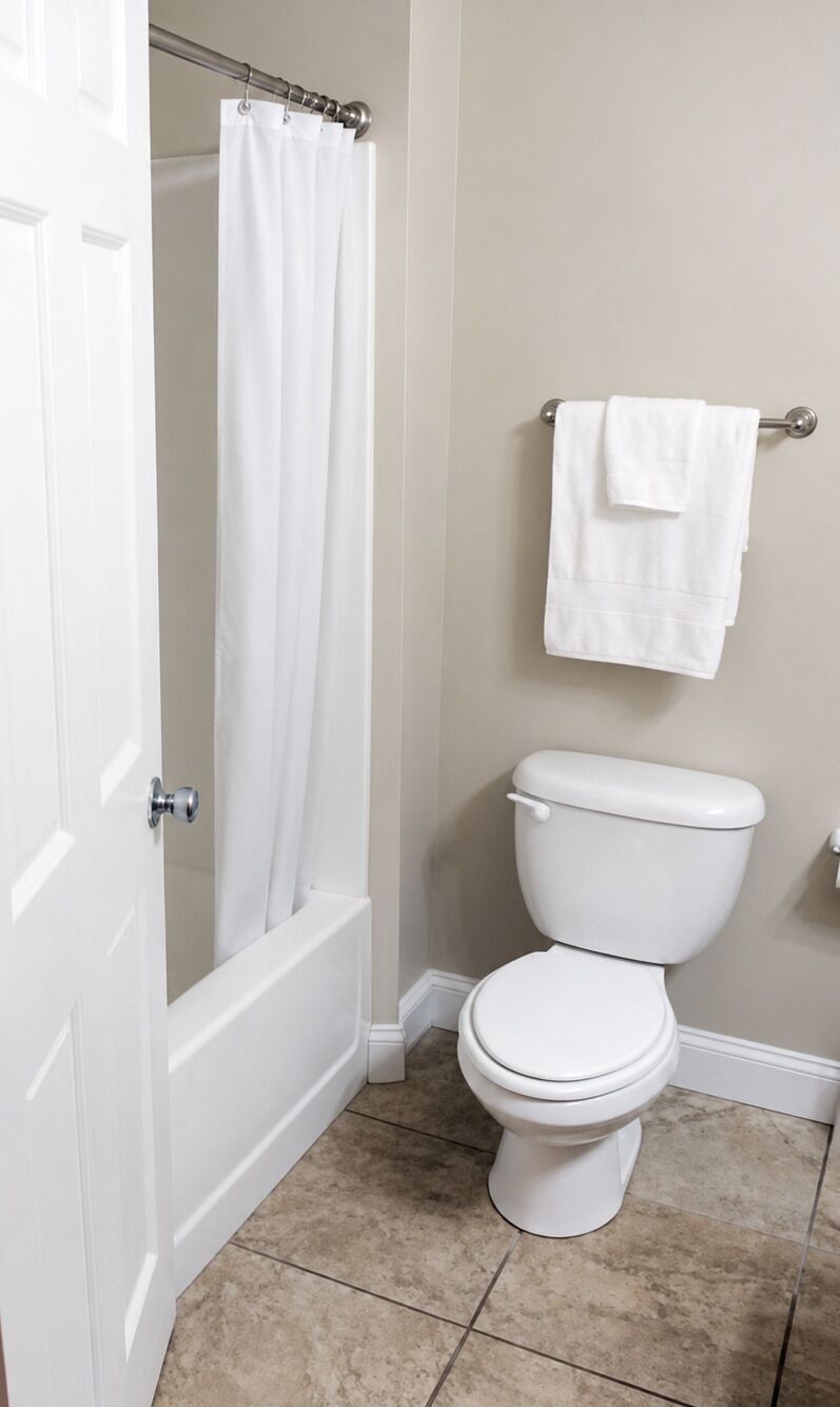 Une salle de bain équipée de toilettes, d’un rideau de douche et d’un porte-serviettes.