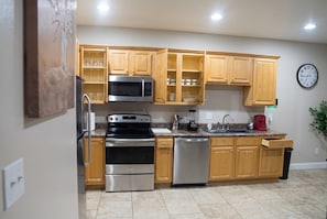 A kitchen with wooden cabinets, stainless steel appliances, a microwave, oven, and dishwasher. - Top Floor · 3BR 2BA · King Beds · Near Shipyard (Moss Point)