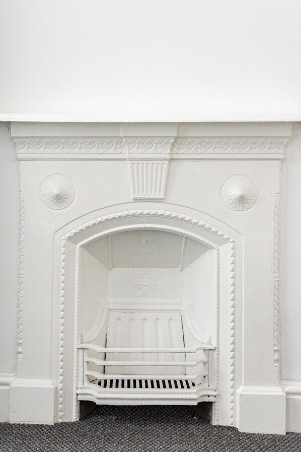 A white fireplace with a bench in front, surrounded by decorative moldings.