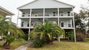 A two-story building with a balcony on the upper floor, surrounded by palm trees. - Rest & Recharge · 3BR · Near Ingalls & Shipyard (Moss Point)