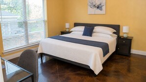 A bedroom with a bed, bedside tables, a chair, a window with blinds, and a painting on the wall. - Ground Floor Stay · 3BR · Parking · Near Refinery (Moss Point)