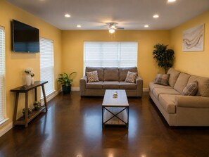 A living room with a sofa, coffee table, and a TV mounted on the wall. - Ground Floor Stay · 3BR · Parking · Near Refinery (Moss Point)