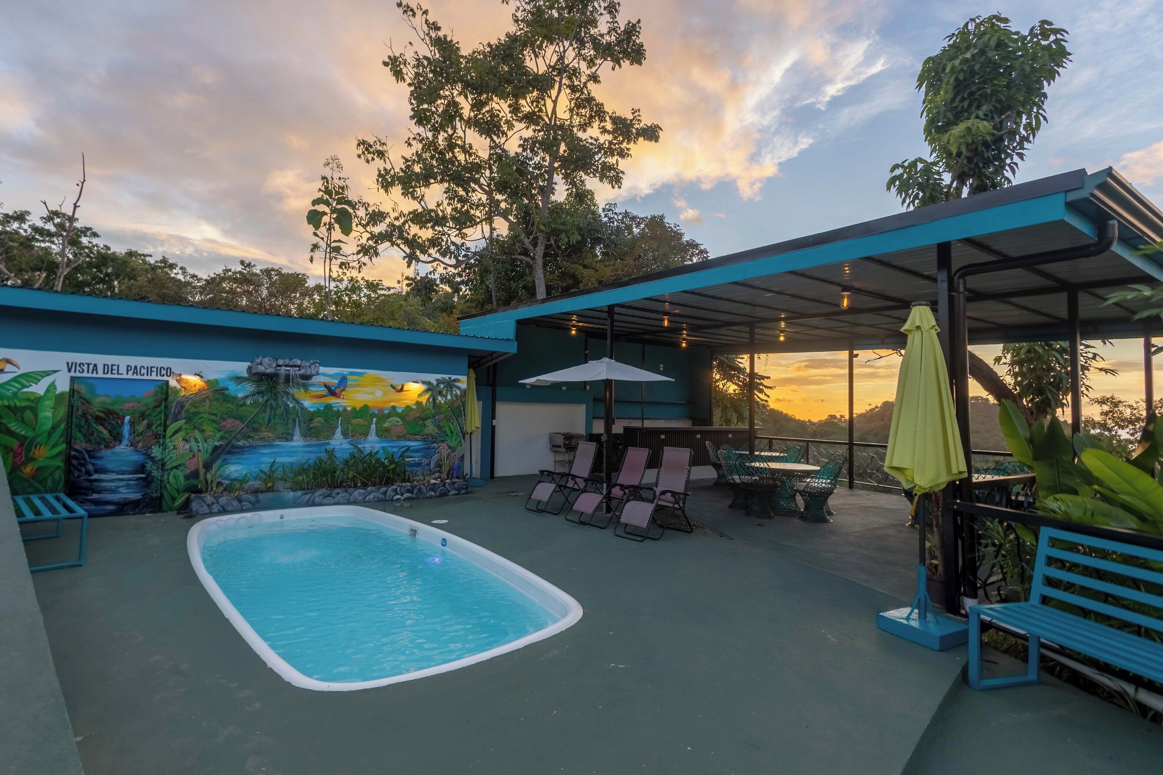 A pool area with a mural, lounge chairs, and a covered seating area.