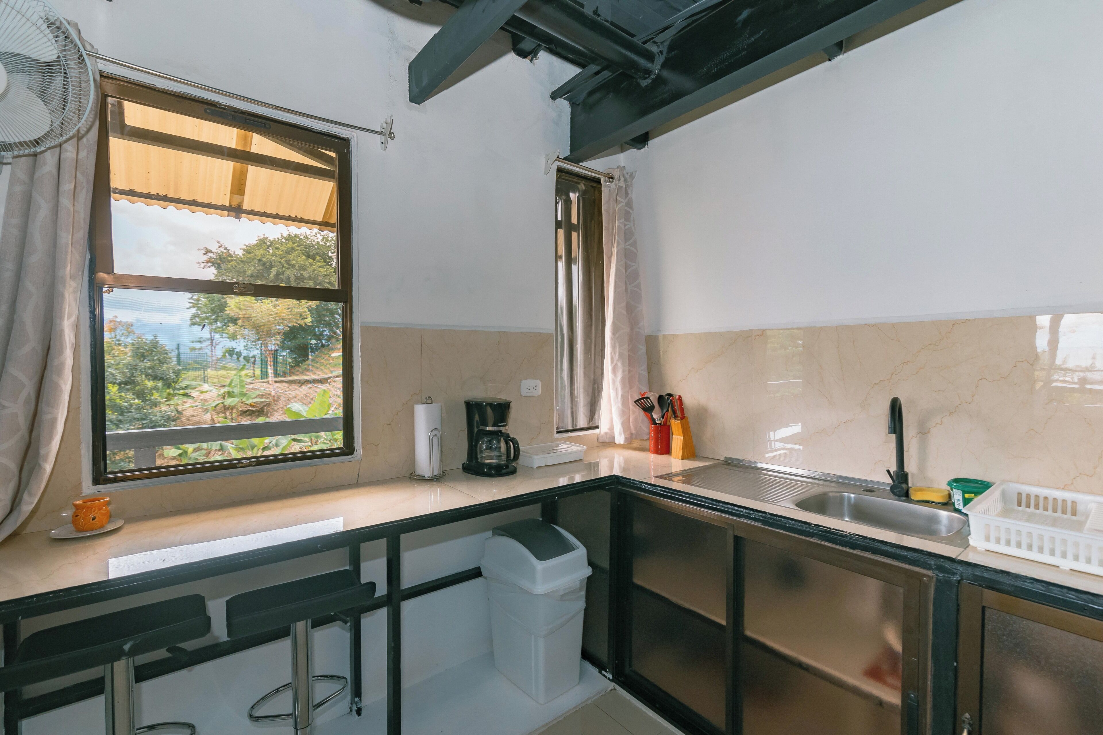 Una cocina compacta con ventana, cafetera y pileta.