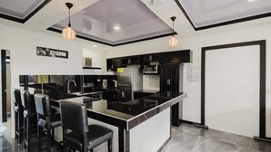 Une cuisine moderne avec des meubles de rangement noirs et blancs, un îlot central doté de tabourets de bar et un éclairage suspendu.