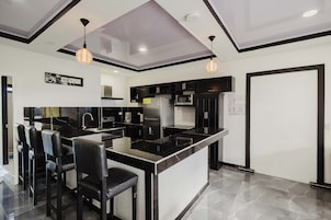 A modern kitchen with black and white cabinetry, a central island with bar stools, and pendant lighting.