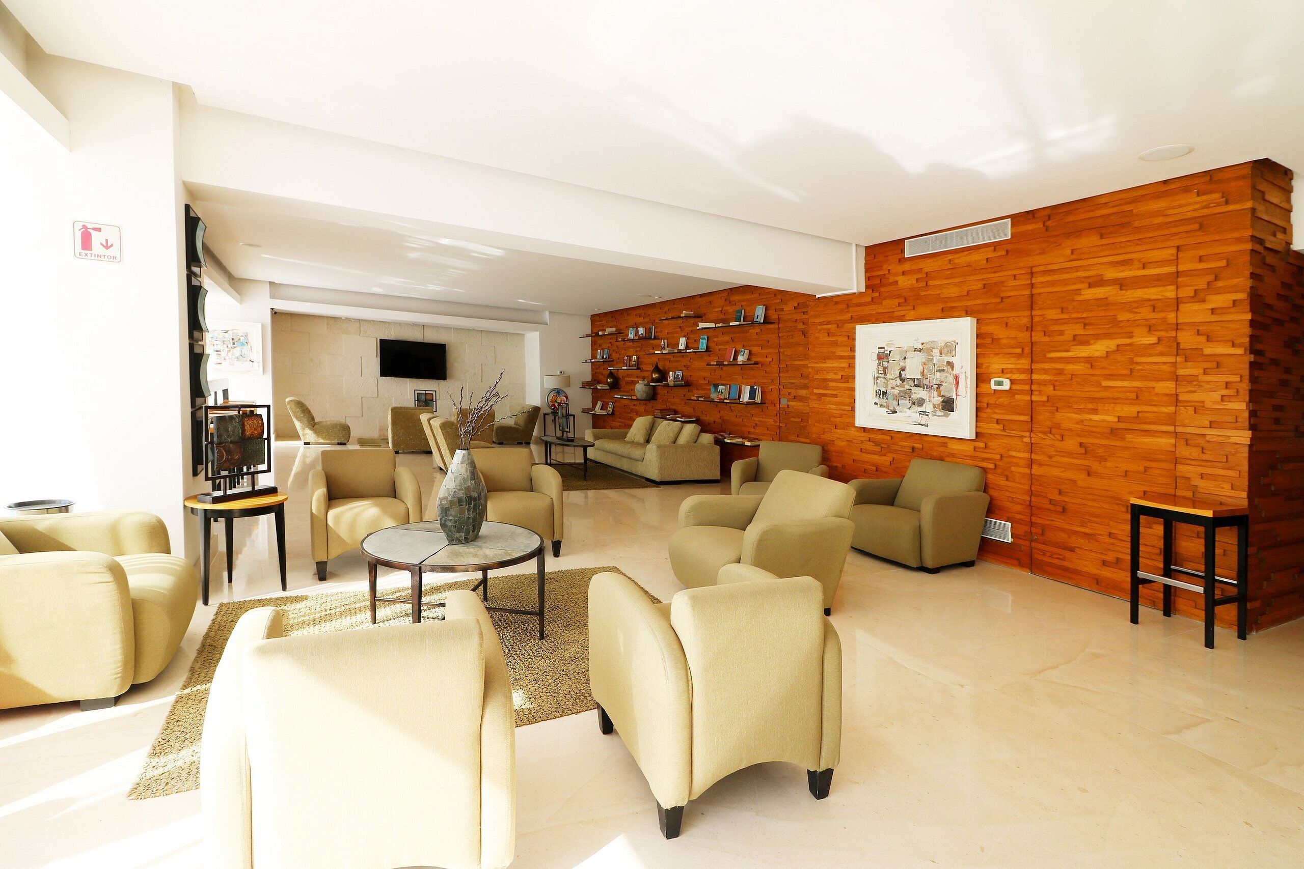 Ein geräumiges Wohnzimmer mit beigen Sofas, einem Couchtisch und einer Wand mit Holzverkleidung.