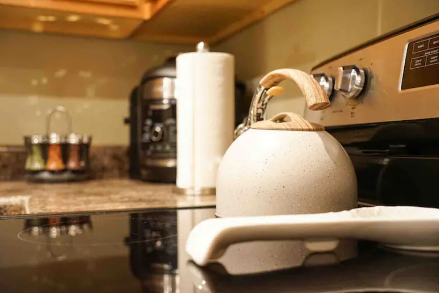 A kitchen with a kettle on the counter, a coffee maker, and a roll of paper towels.