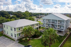 A two-story building with a flat roof, a balcony on the second floor, and a covered front porch. - Ground Floor · 3BR Sleeps 8 · Near Ingalls/Chevron (Moss Point)