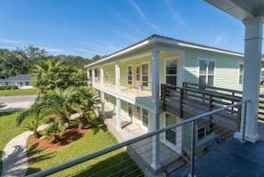 Ein zweistöckiges Haus mit Balkon, einer Palme und blauem Himmel.