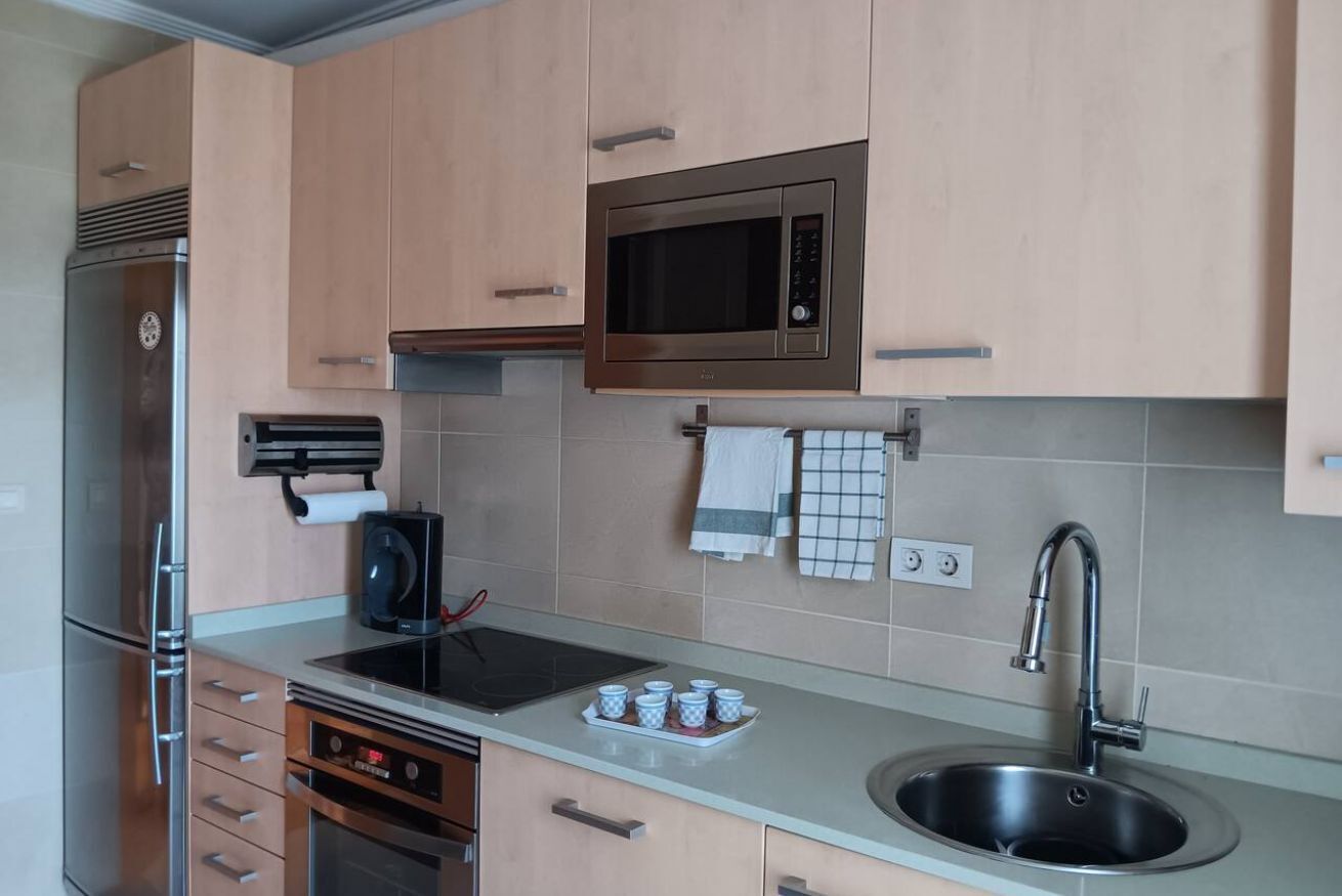 A modern kitchen with stainless steel appliances, a microwave, and a sink.