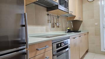Una cocina moderna con electrodomésticos de acero inoxidable, armarios de madera y un microondas.