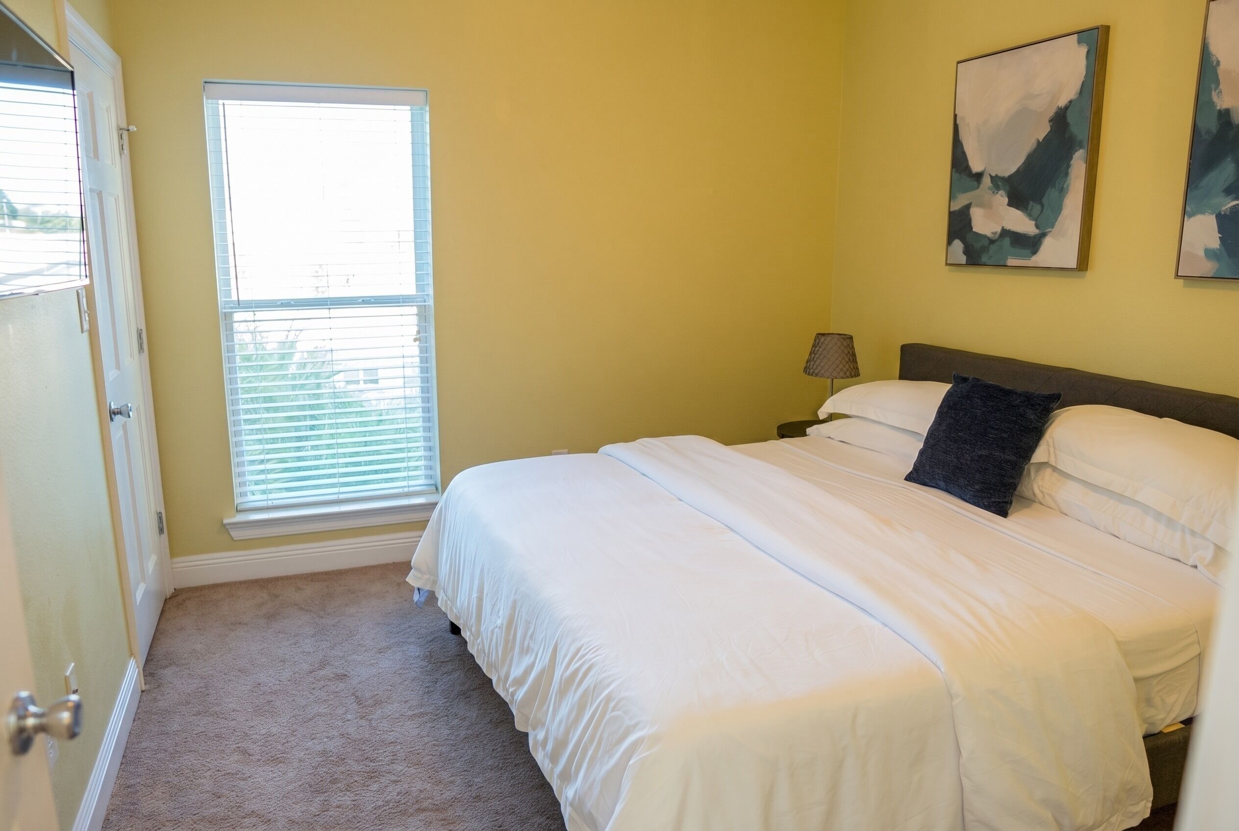 A bedroom with a bed, a window, a nightstand, and a lamp.