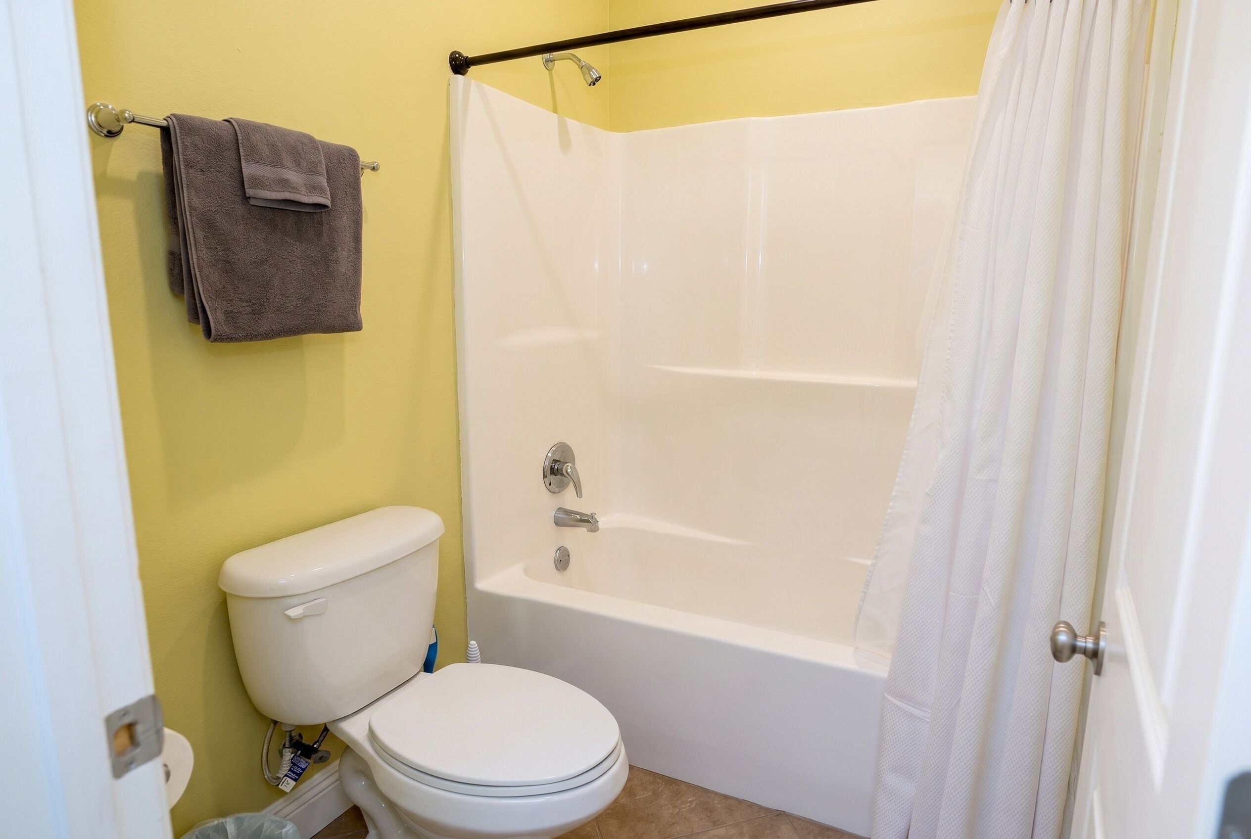 Een badkamer met een wit bad, een toilet en een douchegordijn.