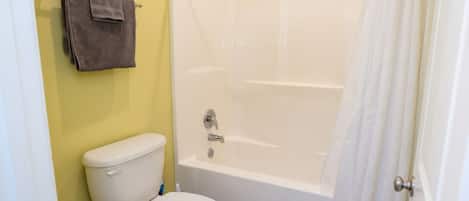 Een badkamer met een wit bad, een toilet en een douchegordijn.