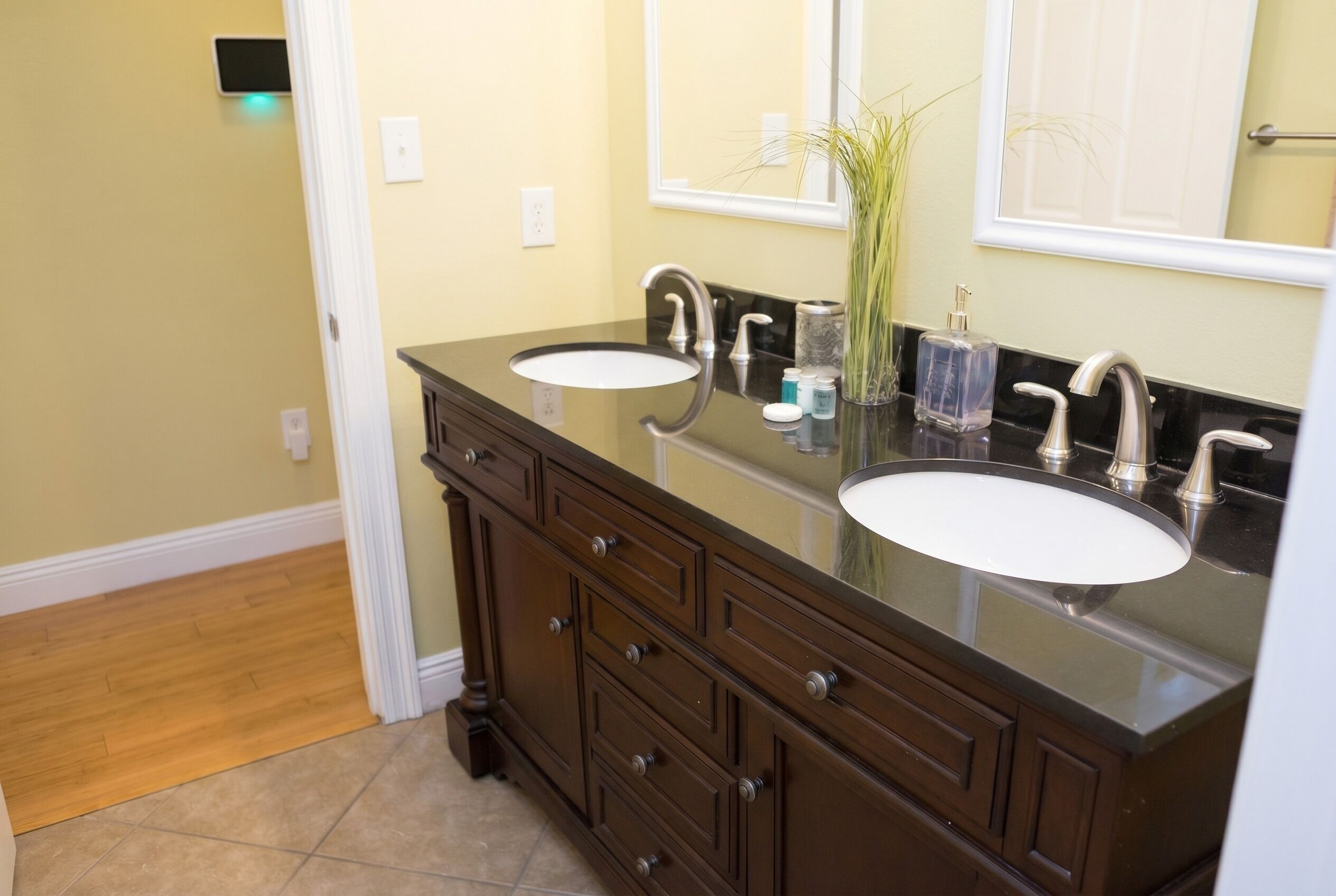 A bathroom with two sinks, dark wooden cabinets, and a mirror above the sink.