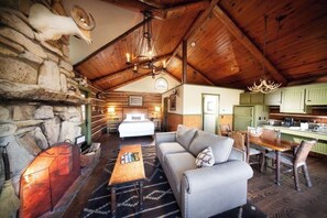 Cozy living area with a stone fireplace, comfortable bed, and dining space.