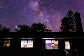 Un bâtiment doté de nombreuses fenêtres, dont certaines sont illuminées, se dressant sur fond de ciel nocturne étoilé.