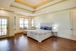 Quarto com cama grande, sofá, mesa pequena e uma porta.