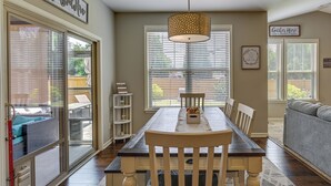 A dining area with a wooden table and chairs, a chandelier, and a view through large windows. - Cozy South Carolina Retreat w/ Patio & Fireplace! (Greenville)