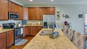 A kitchen with wooden cabinets, a granite countertop, stainless steel appliances, and a coffee-themed wall decal. - Cozy South Carolina Retreat w/ Patio & Fireplace! (Greenville)