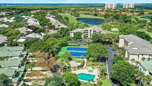 Vista aerea di un resort con diversi edifici, un campo da tennis, una piscina e un campo da golf.