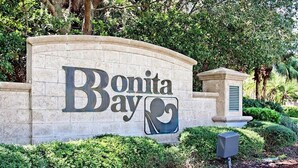Un cartello in pietra con la scritta "Bonita Bay" e un logo stilizzato raffigurante un'onda.
