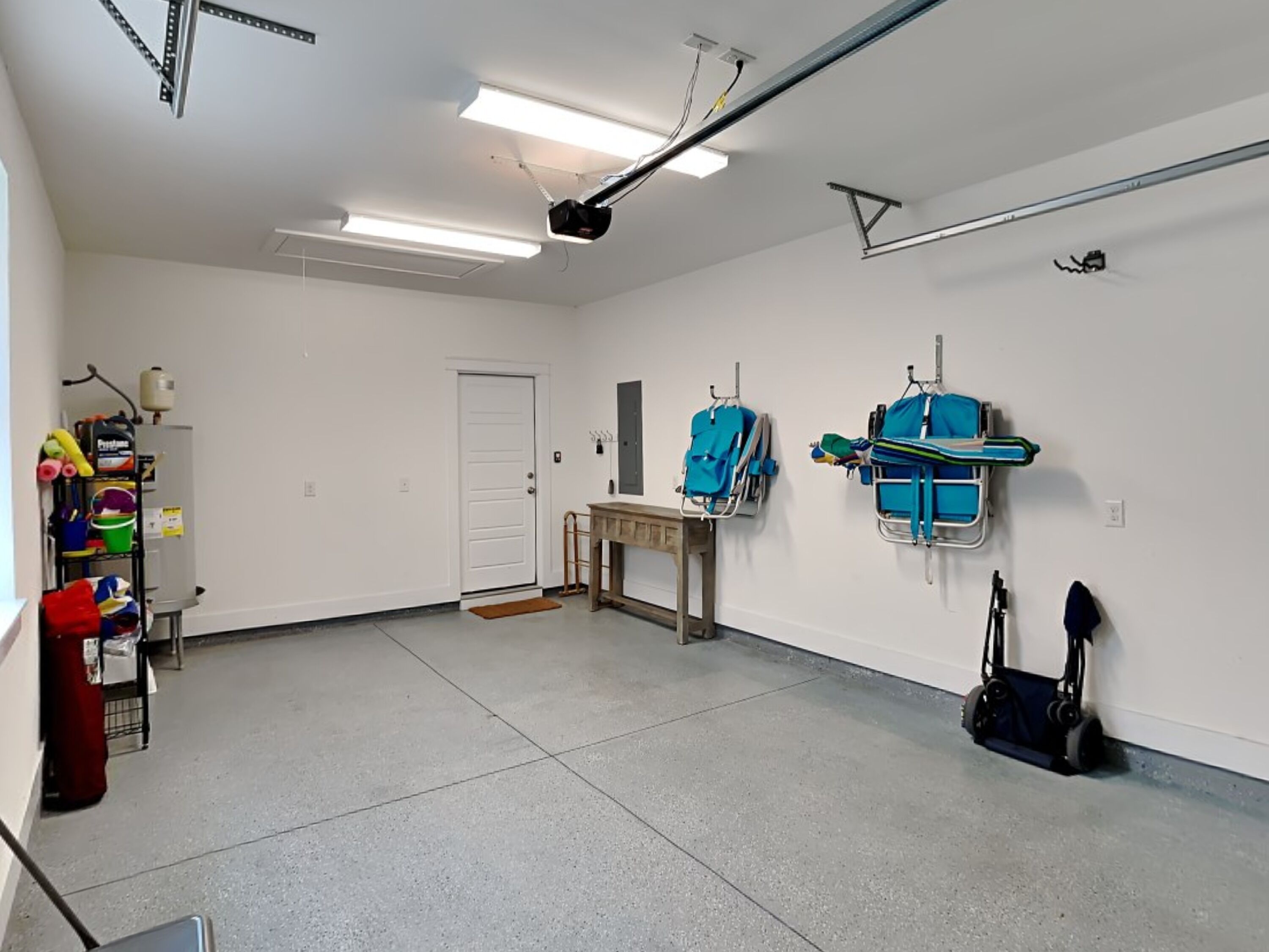 A spacious room with a door, a small table, and two blue medical beds against the wall.