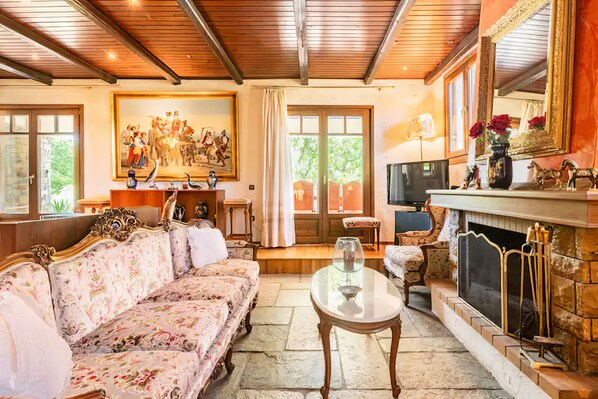 Ein geräumiges Wohnzimmer mit einem großen Sofa, einem Kamin und einem Gemälde an der Wand.