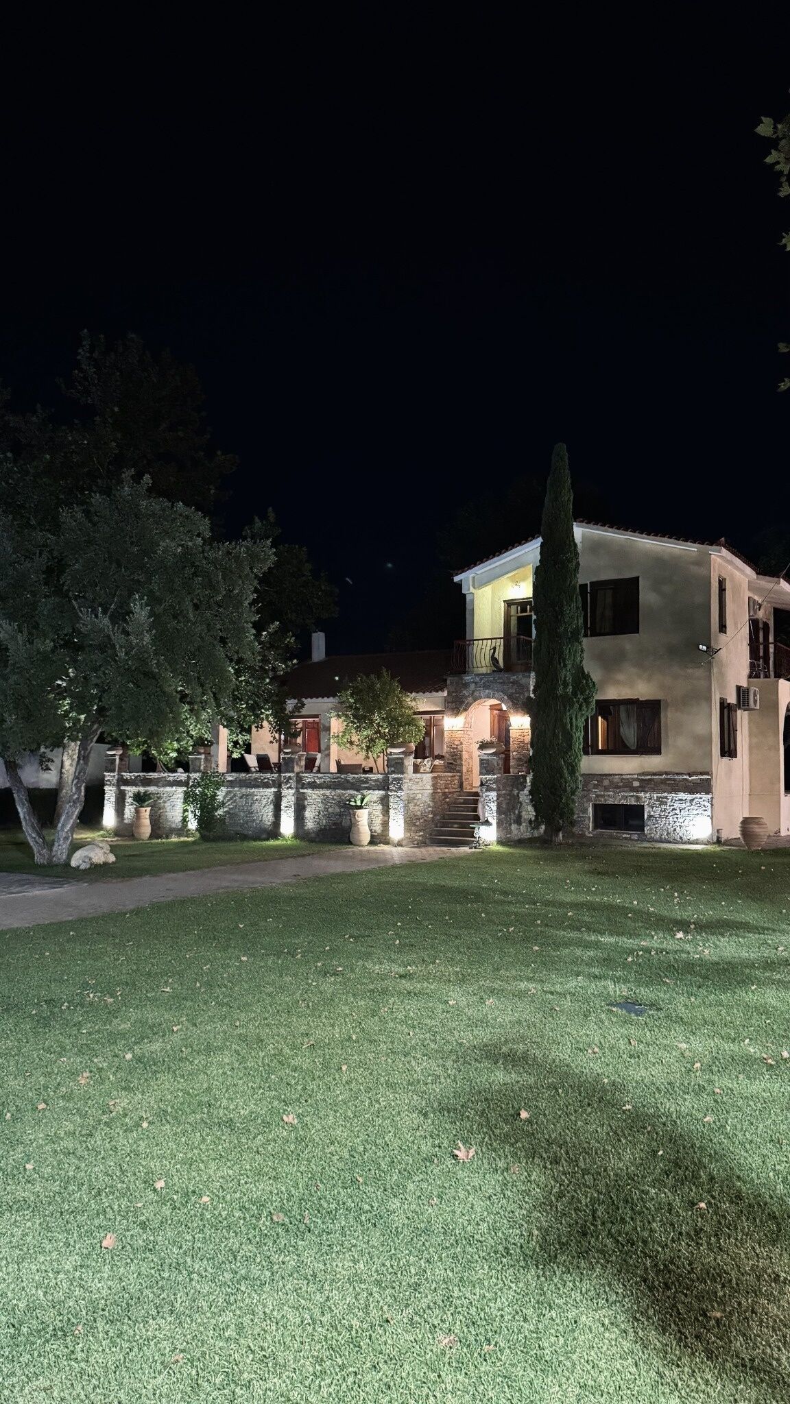 A two-story building with a stone facade, a visible staircase, and a well-maintained lawn.