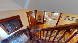 Un escalier en bois mène à un salon où se trouvent un canapé et une pancarte sur laquelle on peut lire : « Bienvenue chez nous ».