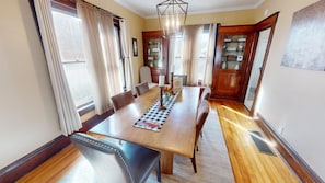 A dining room with a wooden table, chairs, and a chandelier. - 1st Choice Lodging- Maple Leaf Inn (Nelsonville)