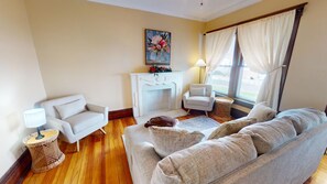 Un salon avec une cheminée, deux canapés, une table basse et un tableau au mur.