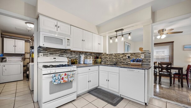 A modern kitchen with white cabinetry, a built-in microwave, and a gas stove.