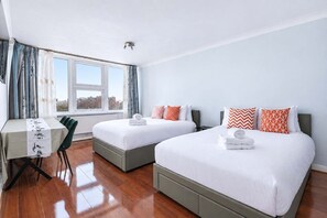 Une chambre d’hôtel avec deux lits, un bureau et une vue sur la ville.