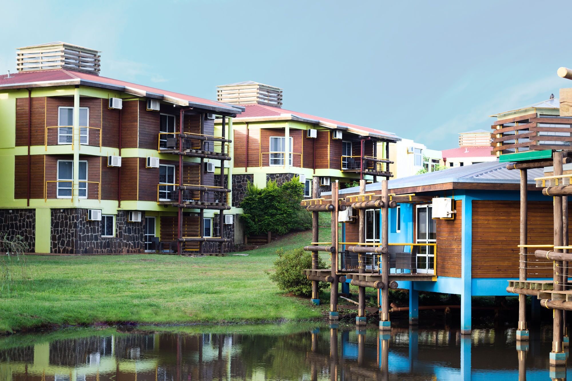 Un edificio a più piani con facciata in legno, balconi e una superficie d'acqua in primo piano.
