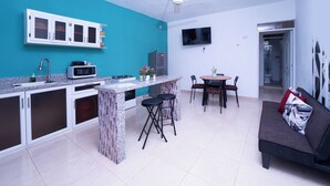 A compact kitchen with a teal accent wall, a dining area with a table and chairs, and a sofa with a cushion. - UNFORGETTABLE STAY/ COCKTAILS/ JACUZZI/ WI-FI/ AC. (Samana)