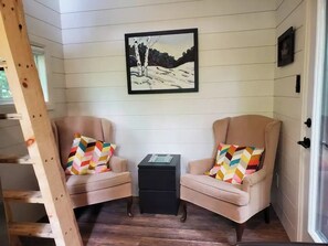 Relax in a peaceful corner with two armchairs, a side table, and a framed painting.